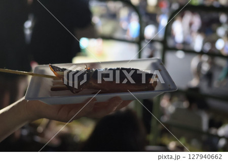 夜景を背景に屋台で買ったイカ焼き 127940662