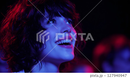 Detailed photo of a young woman 20s with genuine, joyful laughter, looking up at a stage during a vibrant music concert. Detailed photo of a young woman 20s with genuine, joyful laughter, looking up at a stage during a vibrant music concert. 127940947