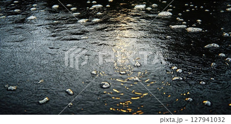 Rain Drops Create Ripples on Water Surface with Golden Light Reflection and Bubbles. 127941032