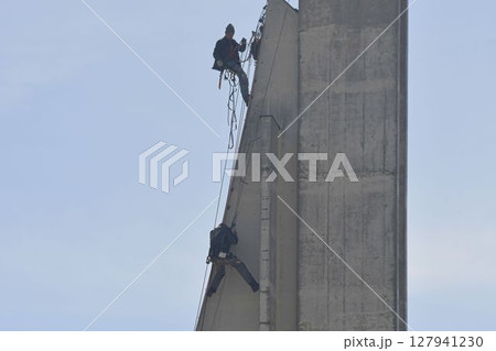 Craftsmen repair the tower of a modern church. Roofers fix the tower of a modern building. The concept of working at heights and work safety Craftsmen repair the tower of a modern church. Roofers fix the tower of a modern building. The concept of working at heights and work safety 127941230