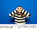 Beautiful Hispanic teenager with braces wearing a striped sweater making a thumbs-up gesture, as if holding binoculars, looking through her fingers. Fun concept 127941345