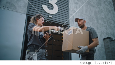 Diverse Employees Carrying Cardboard Boxes to Logistics Warehouse. Female Manager Scanning Parcels 127941571