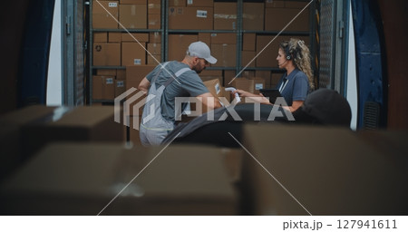 Outside of Logistics Warehouse: Diverse Employees Unloading Delivery Truck with Cardboard Boxes Outside of Logistics Warehouse: Diverse Employees Unloading Delivery Truck with Cardboard Boxes 127941611