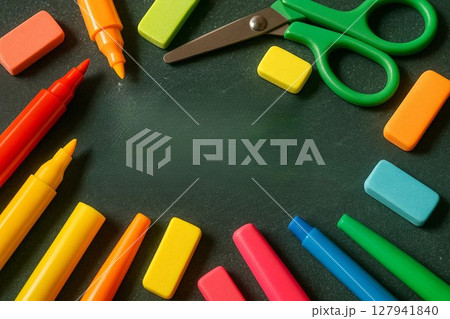 Bright Markers, Erasers, and Scissors Arranged on Black Chalkboard Surface 127941840
