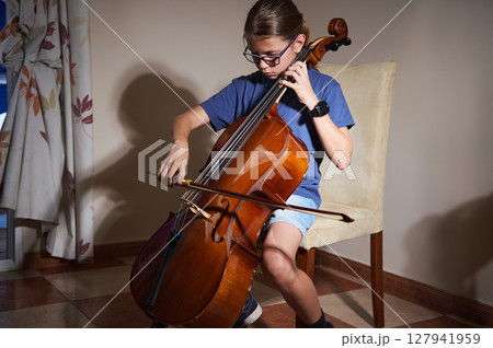 Young Musician Practicing Cello at Home in a Comfortable Setting Using Proper Technique 127941959