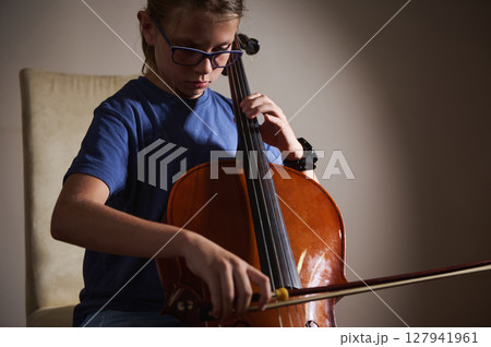 Young Musician Practicing Playing the Cello in a Quiet Setting 127941961