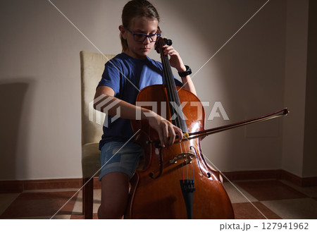 Young Girl Playing Cello in a Warmly Lit Room Demonstrating Musical Talent 127941962