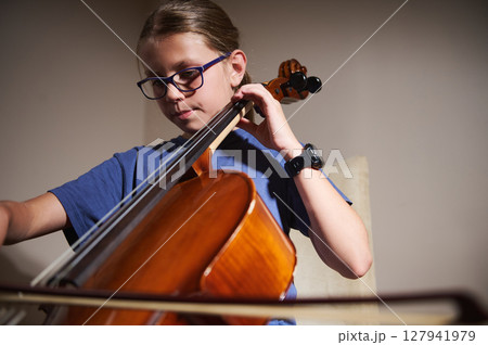 Young Student Practicing Cello at Home Under Soft Lighting 127941979