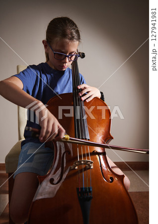 Young Girl Practicing Cello with Focus and Determination in a Minimalist Room Young Girl Practicing Cello with Focus and Determination in a Minimalist Room 127941981