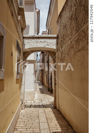 Narrow stone alley with arch. Old European town Porec, Croatia. 127942046