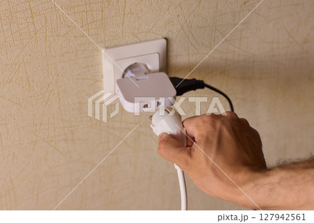 Manually plugging an electrical device into a wall outlet for convenient use and power Manually plugging an electrical device into a wall outlet for convenient use and power 127942561