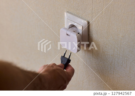 Manually plugging an electrical device into a wall outlet for convenient use and power Manually plugging an electrical device into a wall outlet for convenient use and power 127942567