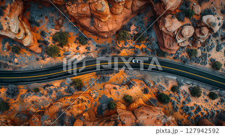 Aerial view of a car driving on a road surrounded by rocks and trees. Picturesque landscape with fantastic rock formations 127942592