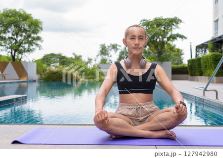 Non-binary person exercising in poolside doing yoga and wearing sport bra Non-binary person exercising in poolside doing yoga and wearing sport bra 127942980