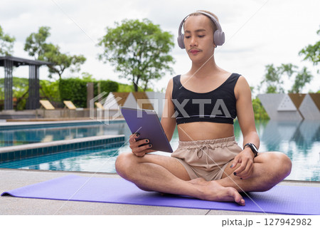 Non-binary person exercising in poolside doing yoga and wearing sport bra 127942982