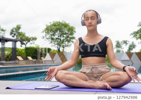 Non-binary person exercising in poolside doing yoga and wearing sport bra 127942986