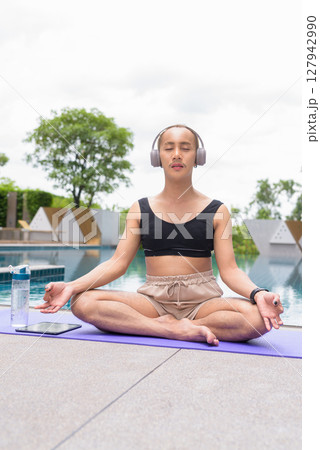 Non-binary person exercising in poolside doing yoga and wearing sport bra 127942990