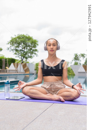 Non-binary person exercising in poolside doing yoga and wearing sport bra Non-binary person exercising in poolside doing yoga and wearing sport bra 127942991