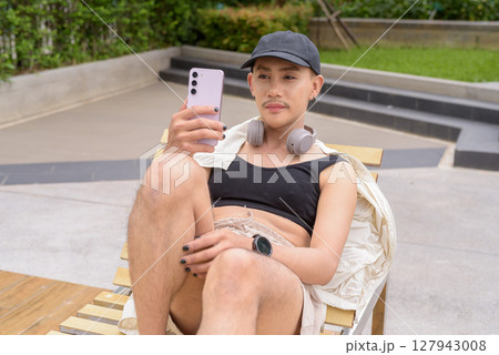 Non-binary person relaxing in poolside during summer wearing sport bra Non-binary person relaxing in poolside during summer wearing sport bra 127943008