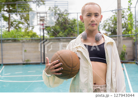 Queer non-binary model holding basketball outdoors 127943044
