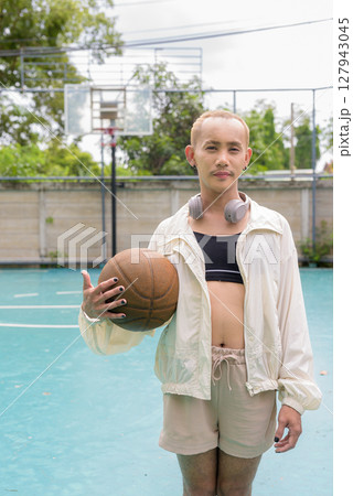 Queer non-binary model holding basketball outdoors Queer non-binary model holding basketball outdoors 127943045