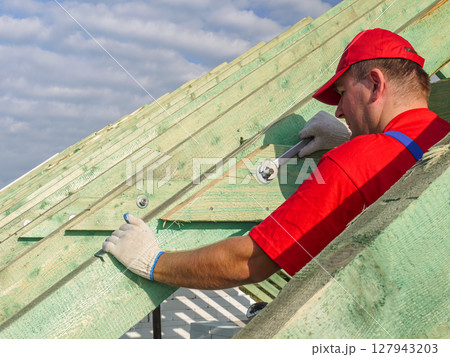 Construction Worker Installing Wooden Roof Frame on a Residential Building 127943203