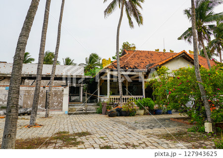 Weathered Colonial House with Palm Trees and Overgrowth in Mui Ne, Vietnam 127943625