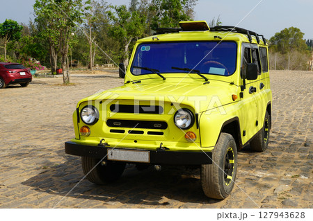 Bright Yellow Off-Road Jeep on Cobblestone Parking Lot in Sunny Mui Ne, Vietnam 127943628