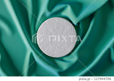 White object is placed on a green fabric 127944706