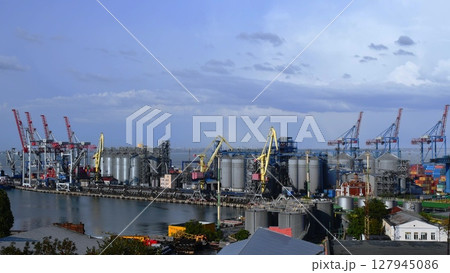 Port landscape with cargo loaders and grain elevators under blue sky 127945086