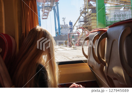 Long haired woman sitting in front of bus window with industrial view behind 127945089