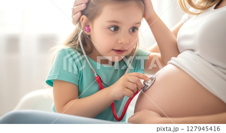 Girl listening to her mother's pregnant belly with stethoscope. 127945416