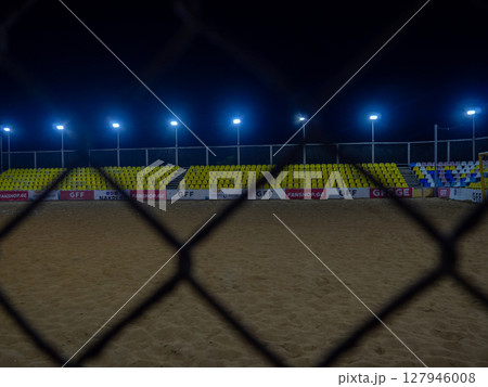Beach soccer field through the fence mesh. Sand play concept. Competition sponsors. View of the viewer 127946008