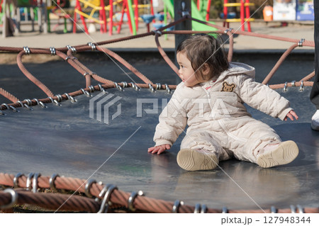 【相模原市立麻溝公園の子どもの広場のトランポリンでママと遊ぶ1歳児】 127948344