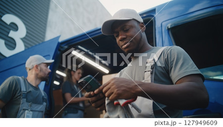 Loader Using Smartphone, Diverse Workers Loading Delivery Truck with Cardboard Boxes 127949609