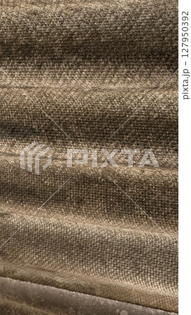 Textured corrugated surface casting subtle light and shadow patterns, likely part of a wall or roofing material. Textured corrugated surface casting subtle light and shadow patterns, likely part of a wall or roofing material. 127950392