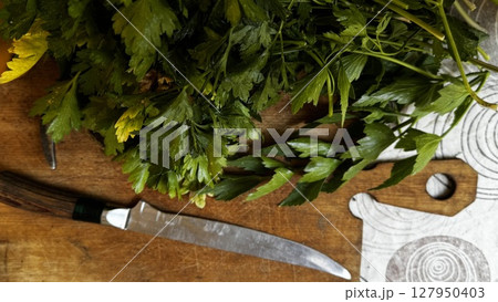 Chopped parsley resting on a wooden cutting board over a patterned surface, prepared for a meal or garnish. 127950403