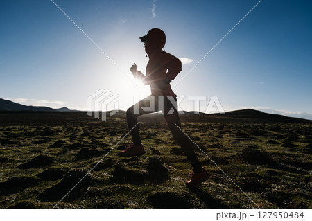 Woman trail runner cross country running to high altitude mountain peak Woman trail runner cross country running to high altitude mountain peak 127950484