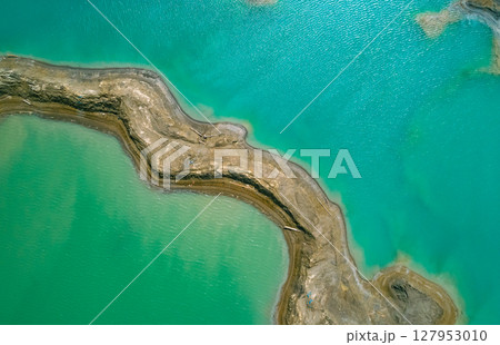 The effects of pollution on a natural habitat, featuring damaged terrain and pools of toxic water surrounded by lush hills. 127953010