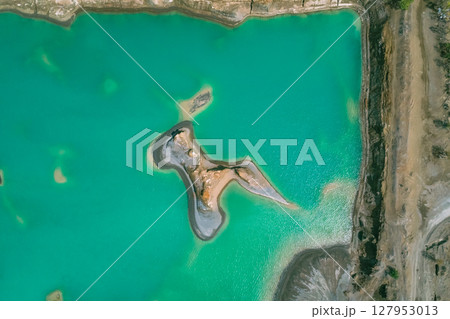 The effects of pollution on a natural habitat, featuring damaged terrain and pools of toxic water surrounded by lush hills. The effects of pollution on a natural habitat, featuring damaged terrain and pools of toxic water surrounded by lush hills. 127953013