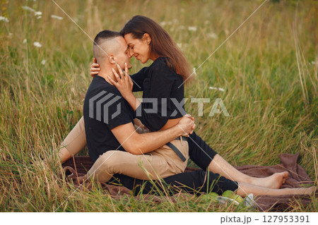 Couple in a field. Woman in a black blouse. Sunset background. 127953391