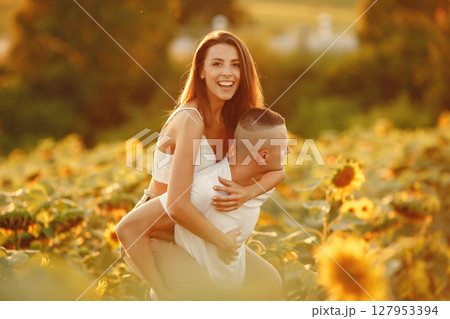 Young loving couple is kissing in a sunflower field. Portrait of couple posing in summer in field. 127953394