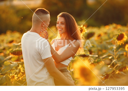 Young loving couple is kissing in a sunflower field. Portrait of couple posing in summer in field. 127953395