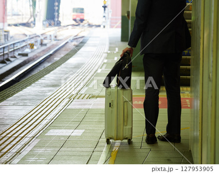駅のホームで電車街のスーツケースを持つサラリーマンの姿 127953905