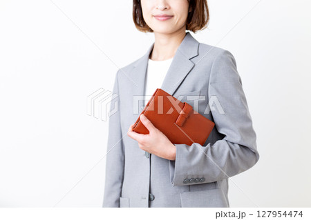 手帳を持つスーツ姿のミドル女性 127954474
