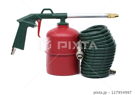 A close-up shot of an industrial air gun with a green hose and air tank on white background. A close-up shot of an industrial air gun with a green hose and air tank on white background. 127954997