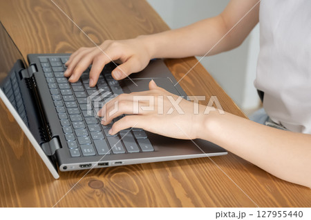 ノートパソコンで作業をする女の子の手元 127955440