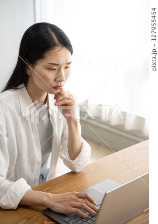 パソコンの前で悩む女性 127955454
