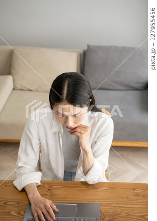 パソコンの画面を見て悩む女性 127955456