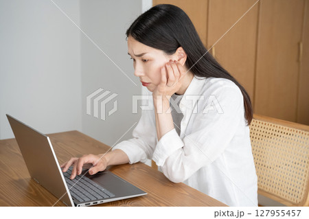 パソコンの画面を見て悩む女性 127955457